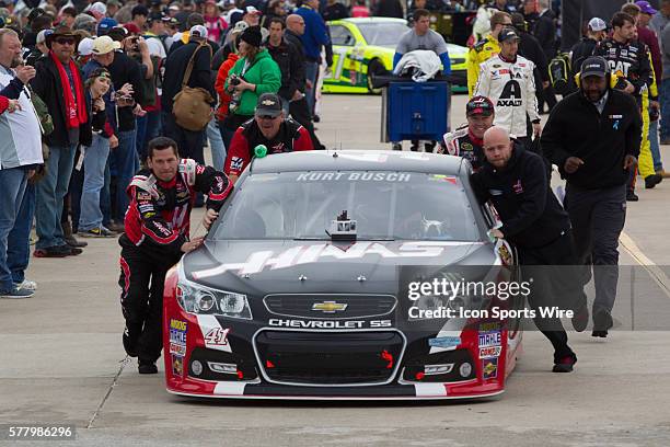 Crew members of Kurt Busch, driver of the Haas Automation Chevrolet push the car to the starting grid before Busch finished 39th in the rain delayed...