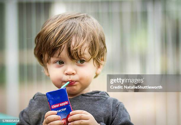 young boy drinking a juice box - ジュースパック ストックフォトと画像