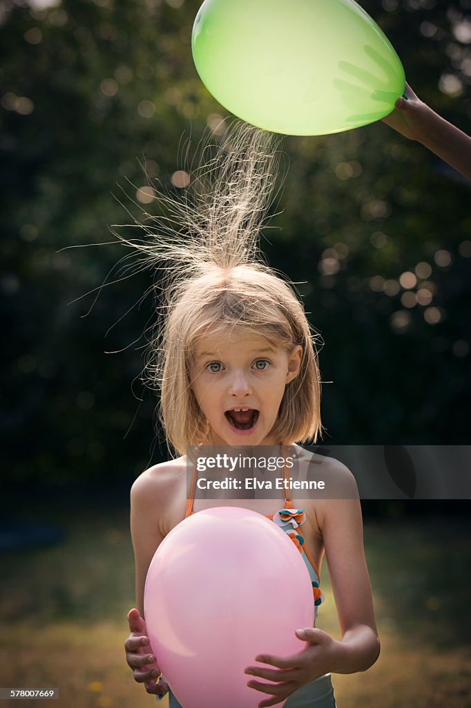 Girl (7-8 years) with static hair and balloons