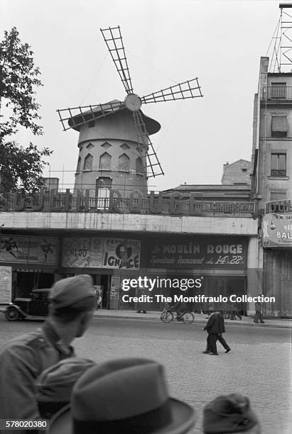 German soldier looks up at the Moulin Rouge during the 2nd World War German occupation of France. The German Occupation 'Guide aryien' counts the...