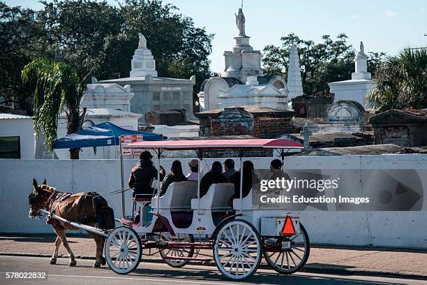 Horse-drawn carriage passes St. Louis cemetery, New Orleans, Louisiana.