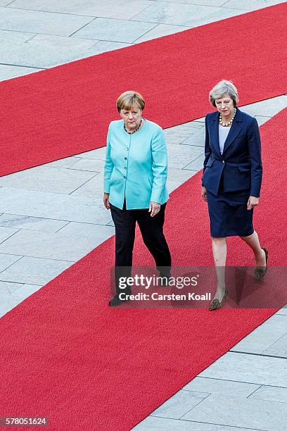 German Chancellor Angela Merkel and British Prime Minister Theresa May walk on a red carpet while reviewing a guard of honor upon May's arrival at...