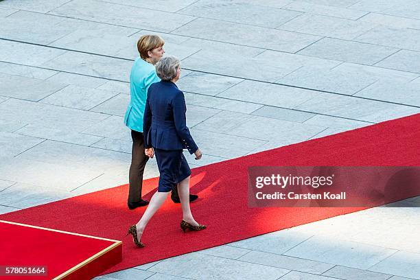 German Chancellor Angela Merkel and British Prime Minister Theresa May walk on a red carpet while reviewing a guard of honor upon May's arrival at...