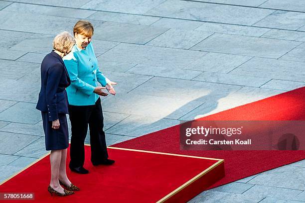 German Chancellor Angela Merkel and British Prime Minister Theresa May walk on a red carpet while reviewing a guard of honor upon May's arrival at...