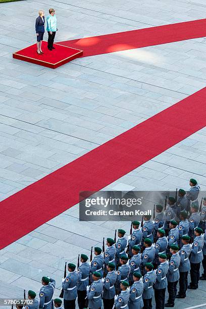 German Chancellor Angela Merkel and British Prime Minister Theresa May walk on a red carpet while reviewing a guard of honor upon May's arrival at...