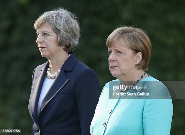 German Chancellor Angela Merkel and British Prime Minister Theresa May listen to their nations' respective national anthems upon May's arrival at the...