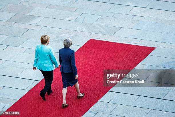 German Chancellor Angela Merkel and British Prime Minister Theresa May walk on a red carpet while reviewing a guard of honor upon May's arrival at...