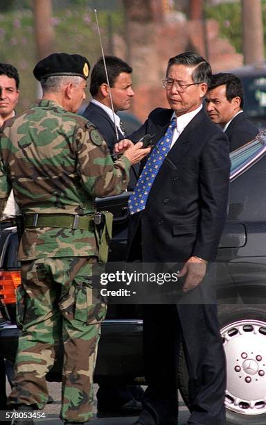 Peruvian President Alberto Fujimori receives cellular telephone from unidentified military officer 23 October 2000 near the headquarters of the...