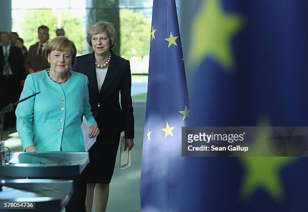 German Chancellor Angela Merkel and British Prime Minister Theresa May walk past European Union flags as they arrive to speak to the media following...