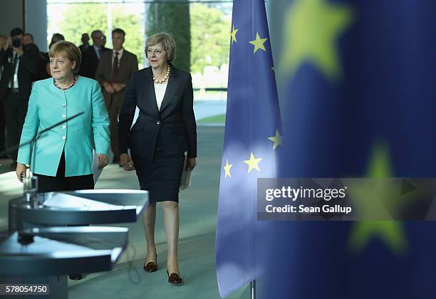 German Chancellor Angela Merkel and British Prime Minister Theresa May walk past European Union flags as they arrive to speak to the media following...