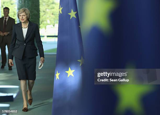 British Prime Minister Theresa May walks past European Union flags as she and German Chancellor Angela Merkel arrive to speak to the media following...