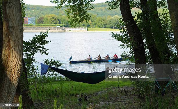 Man relaxes on a hammock at sunset while a rowing boat on the river Rhine moves on July 20, 2016 in Bonn, Germany. All over Germany is enjoying...