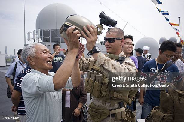 Staff Sgt Max Veliz, a Marine assigned to Fleet Anti-Terrorism Security Team FAST Company Pacific, 3rd Platoon, puts a helmet on a visitor during an...