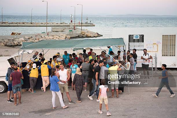 volunteers are serving dinner for refugees in greek refugee camp - quiosque stock pictures, royalty-free photos & images