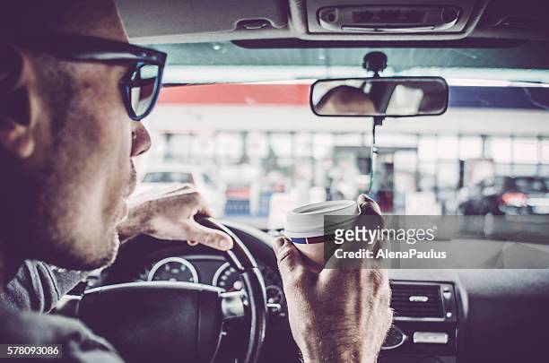 man driving his car and drinking take away coffee - drink driving stockfoto's en -beelden