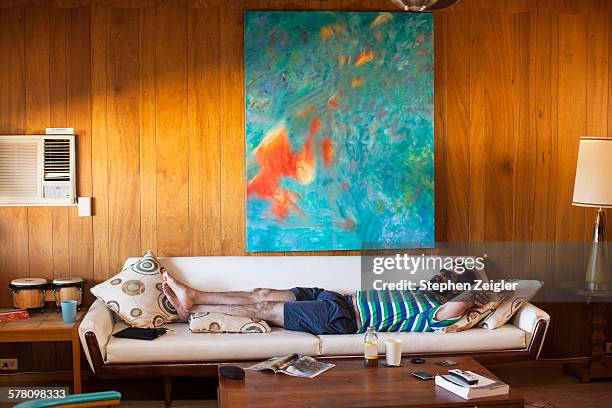 man laying on sofa - liegen stock-fotos und bilder