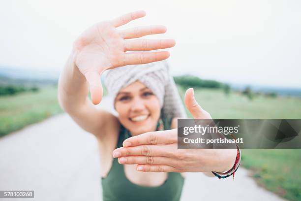 juguetona mujer joven en el camino rural haciendo marco de dedo - shawl fotografías e imágenes de stock