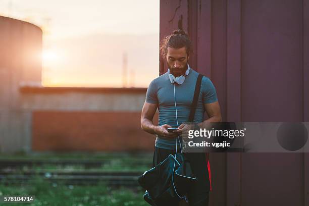 athletic man using his smart phone after running. - gym bag stock pictures, royalty-free photos & images
