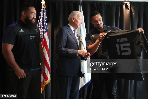 Vice President Joe Biden receives a personalised All Black rugby jersey from players Jerome Kaino and Charlie Faumuina during his visit to Auckland...