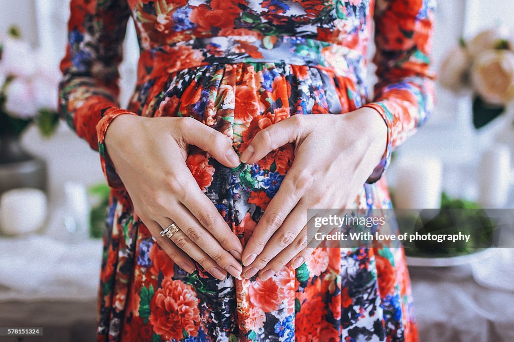 Heart made of hands on pregnant belly babybump, future mother's love