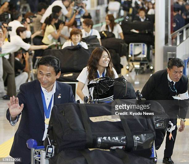 Japan - Coach Norio Sasaki and captain Homare Sawa of Japan's national women's soccer team smile at fans at Narita International Airport in Chiba...