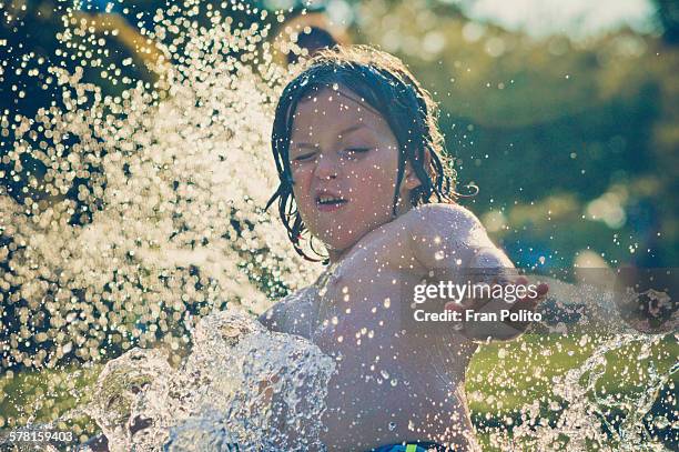 boy outside playing in the slip and slide. - backyard water slide stock pictures, royalty-free photos & images