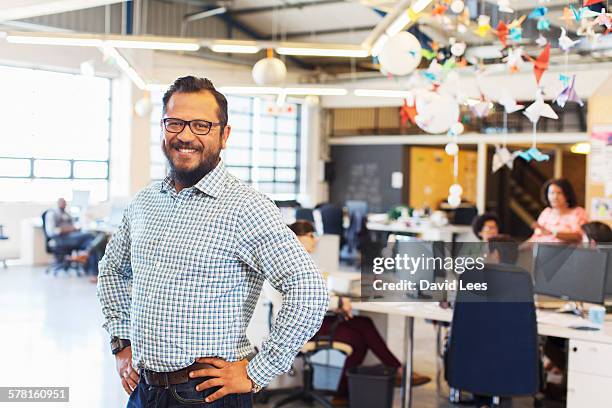 smiling businessman in modern office - hand on hip stock pictures, royalty-free photos & images