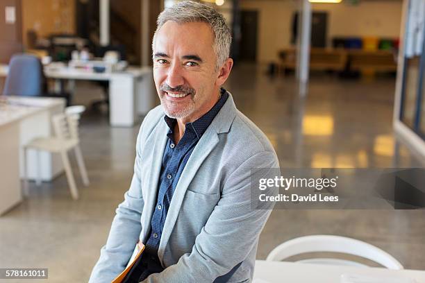 smiling businessman in modern office - white blazer 個照片及圖片檔