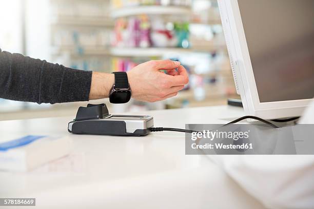 customer paying cashless with smartwatch in a pharmacy - watch payment stock pictures, royalty-free photos & images