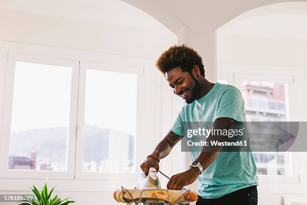 young man ironing shirt at home - ironing stock pictures, royalty-free photos & images