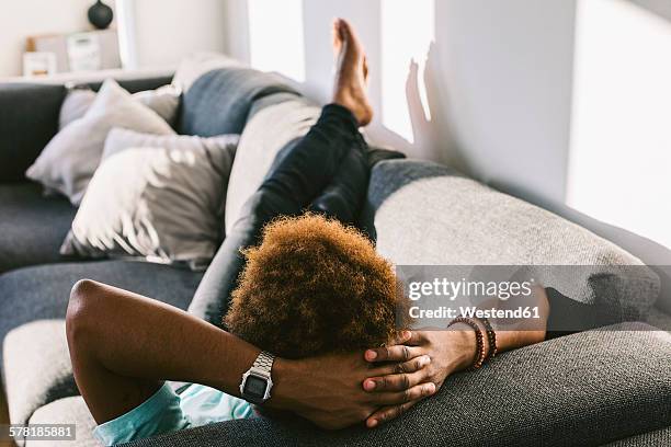 young man at home relaxing on couch - feet up stock pictures, royalty-free photos & images