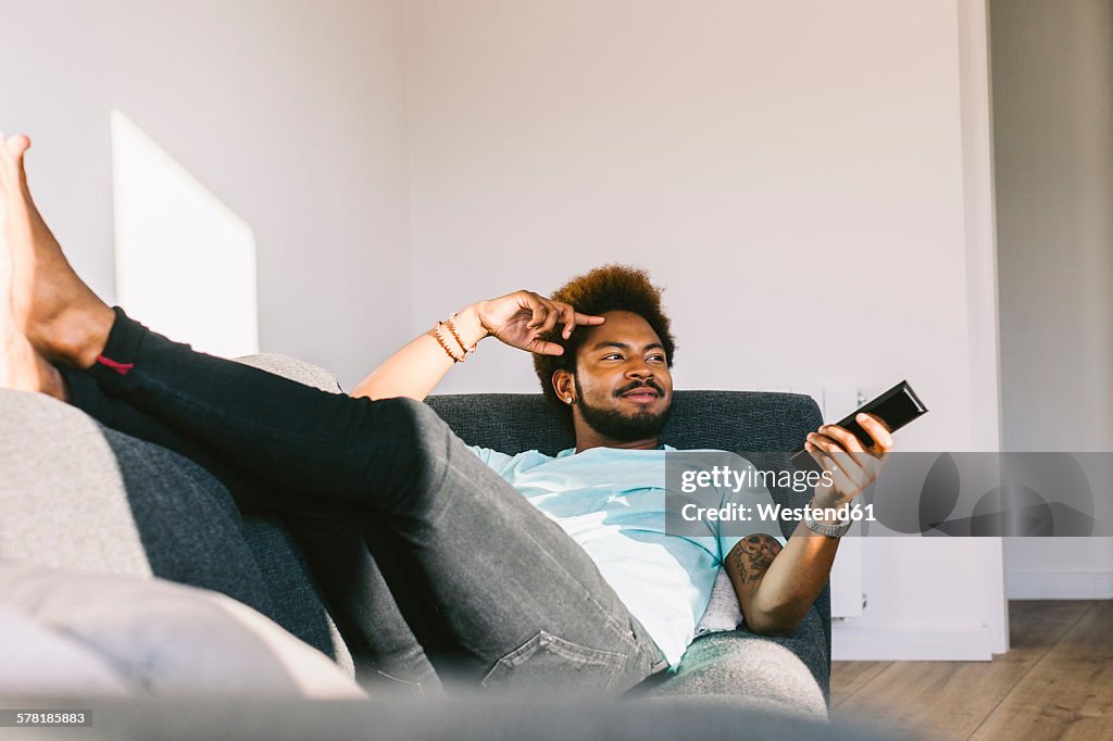 Young man lying on couch watching TV