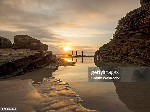 spain, galicia, ribadeo, playa de aguas santas at sunset, small persons at beach - galizien stock-fotos und bilder