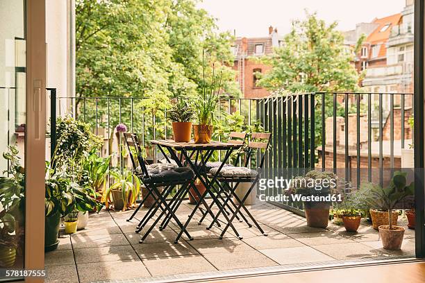 bistro chairs and table on balcony with view in the yard - balkon pflanzen stock-fotos und bilder