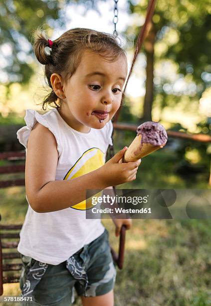 little girl trying to eat ice cream - girl eating messy ice cream cone stock pictures, royalty-free photos & images