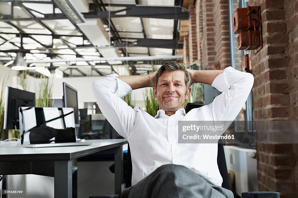 Portrait of smiling businessman in office relaxing