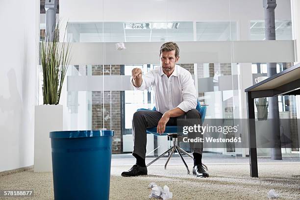 businessman in office throwing crumpled paper in wastepaper basket - throwing paper stock pictures, royalty-free photos & images