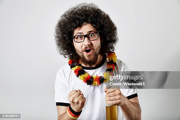 portrait of excited young man with beer bottle and german football fan articles - beer bottle mouth stock-fotos und bilder