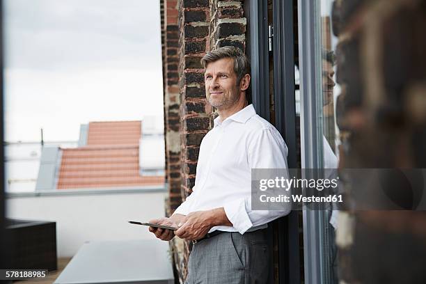 smiling businessman with digital tablet on roof terrace - dachterasse stock-fotos und bilder