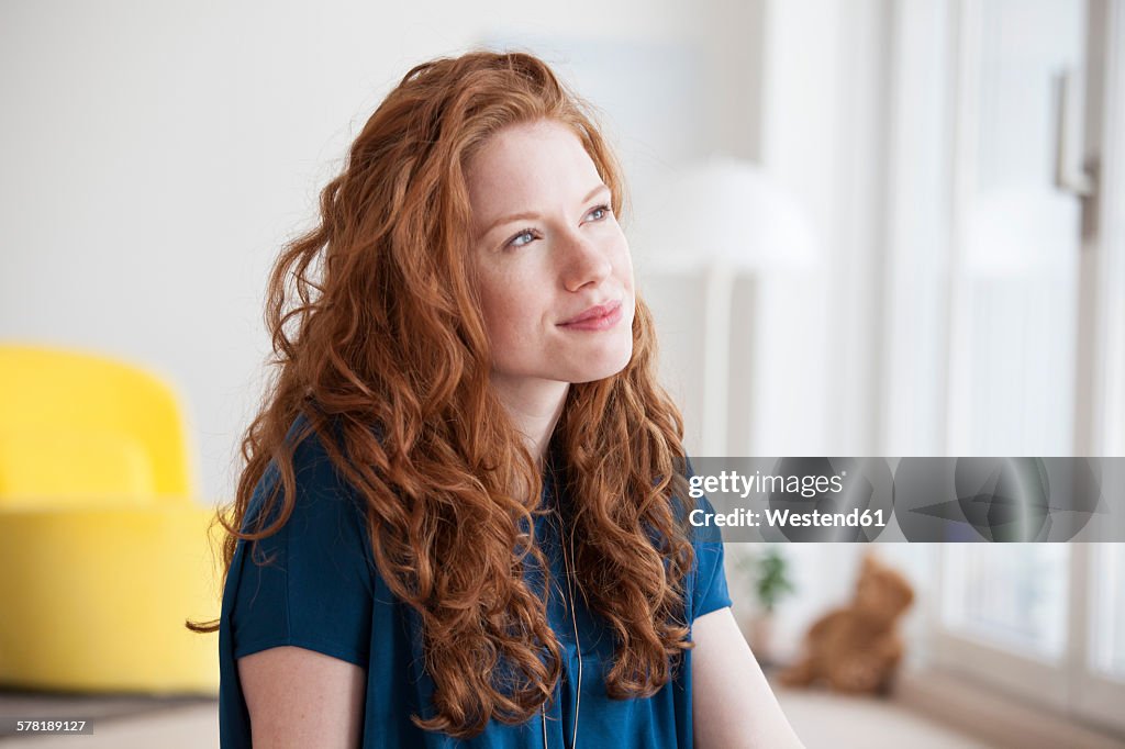 Portrait of daydreaming young woman at home