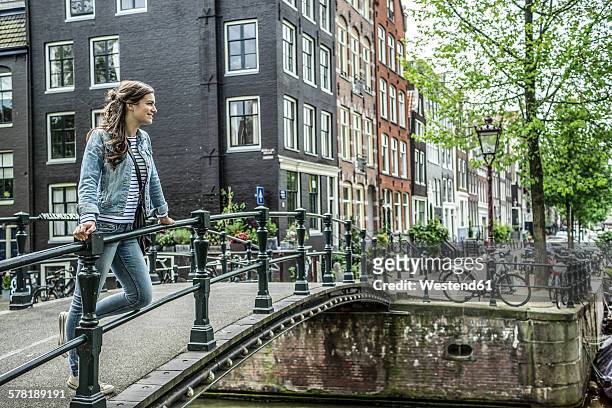 netherlands, amsterdam, female tourist standing on footbridge - amsterdam people stock pictures, royalty-free photos & images
