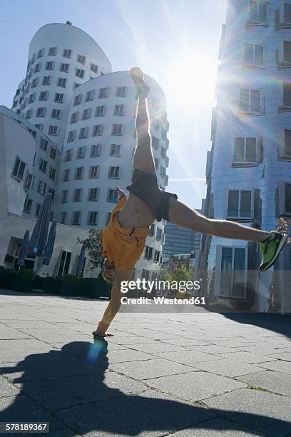 germany, duesseldorf, athlete doing a handstand at media harbor - düsseldorf medienhafen stock pictures, royalty-free photos & images