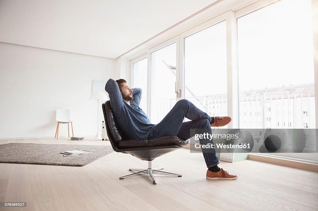 Young man relaxing on leather chair in his living room