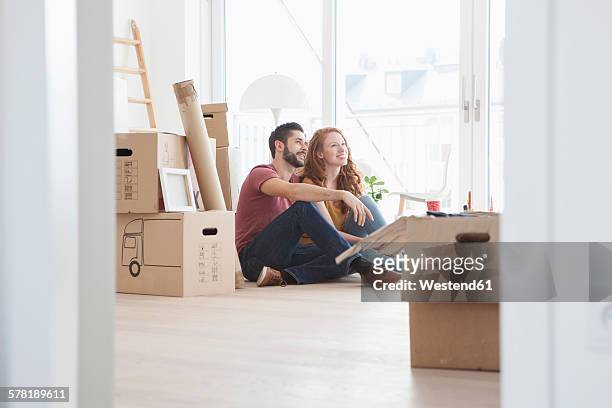 young couple in new flat with cardboard boxes - young adult moving out stock pictures, royalty-free photos & images