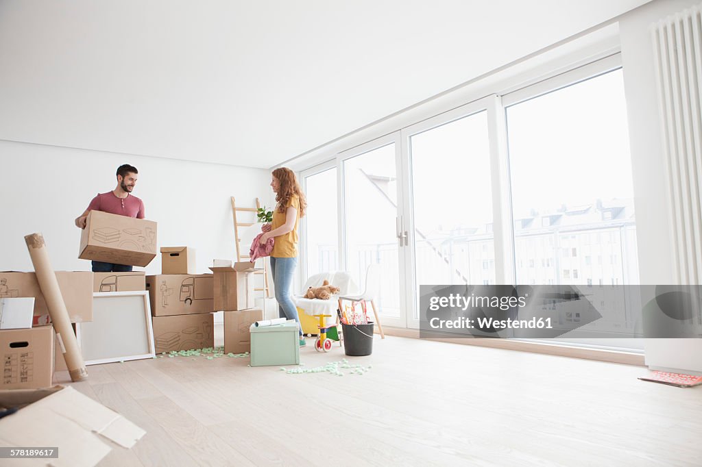 Young couple in new flat unpacking cardboard boxes
