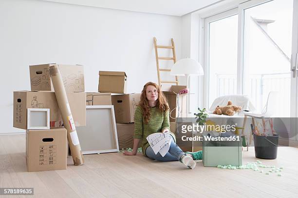 young woman in new flat with cardboard boxes holding ground plan - person on the move stock pictures, royalty-free photos & images