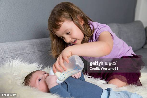 little girl feeding newborn brother with baby bottle - sisters feeding bildbanksfoton och bilder