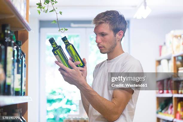 male shop assistant sorting merchandise in wholefood shop - oil prices stock-fotos und bilder