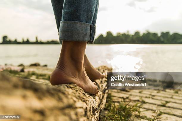 close-up of young woman balancing on log by the riverside - barefeet stock-fotos und bilder