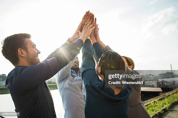 four happy businesspeople raising their hands together - business people cheering stockfoto's en -beelden